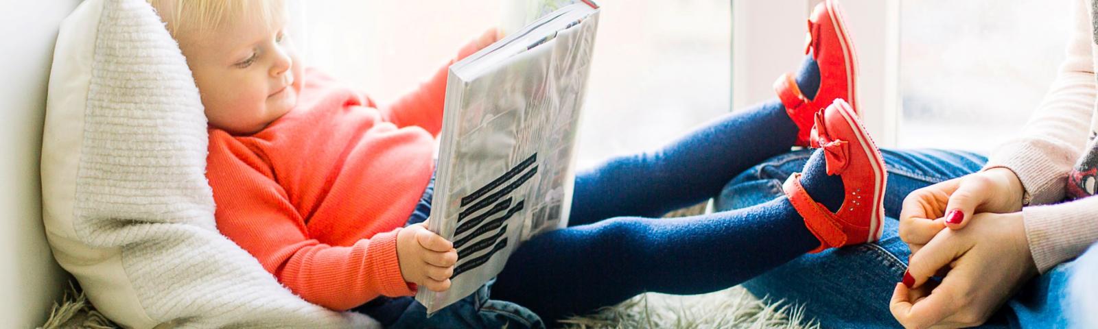 Child reading book with parent