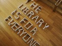 View from above of books on a library floor, spelling the message "the Library is for Everyone"